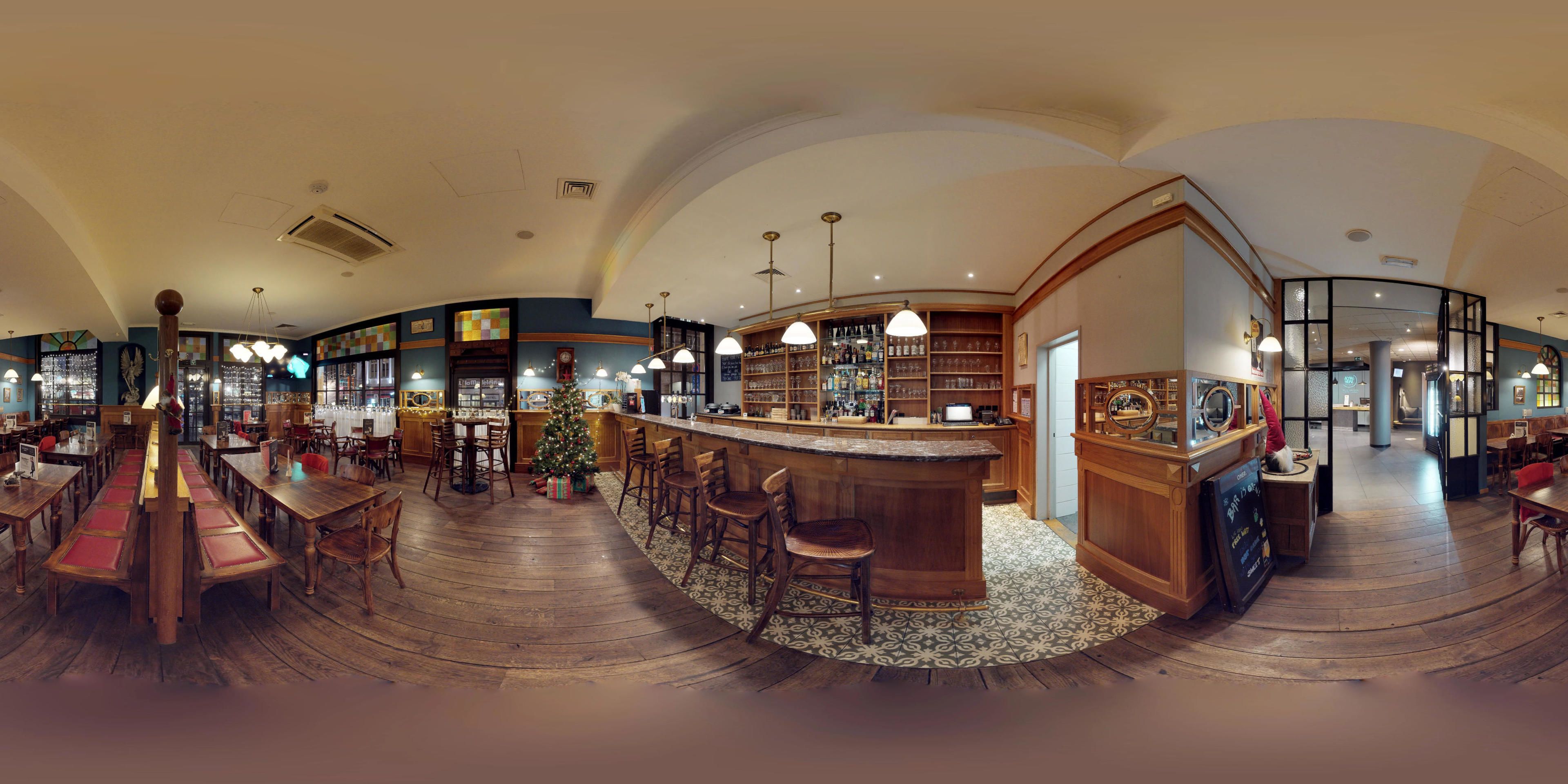Un restaurant spacieux doté d’un bar central, d’un plancher en bois et d’un sapin de Noël.