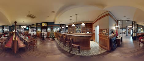 Un restaurante espacioso con barra central, piso de madera y un árbol de Navidad.