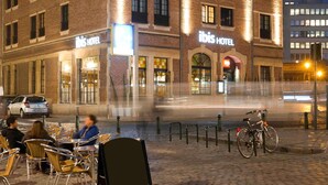 Een hotel met een bakstenen gevel, een terras en een fiets voor de deur.