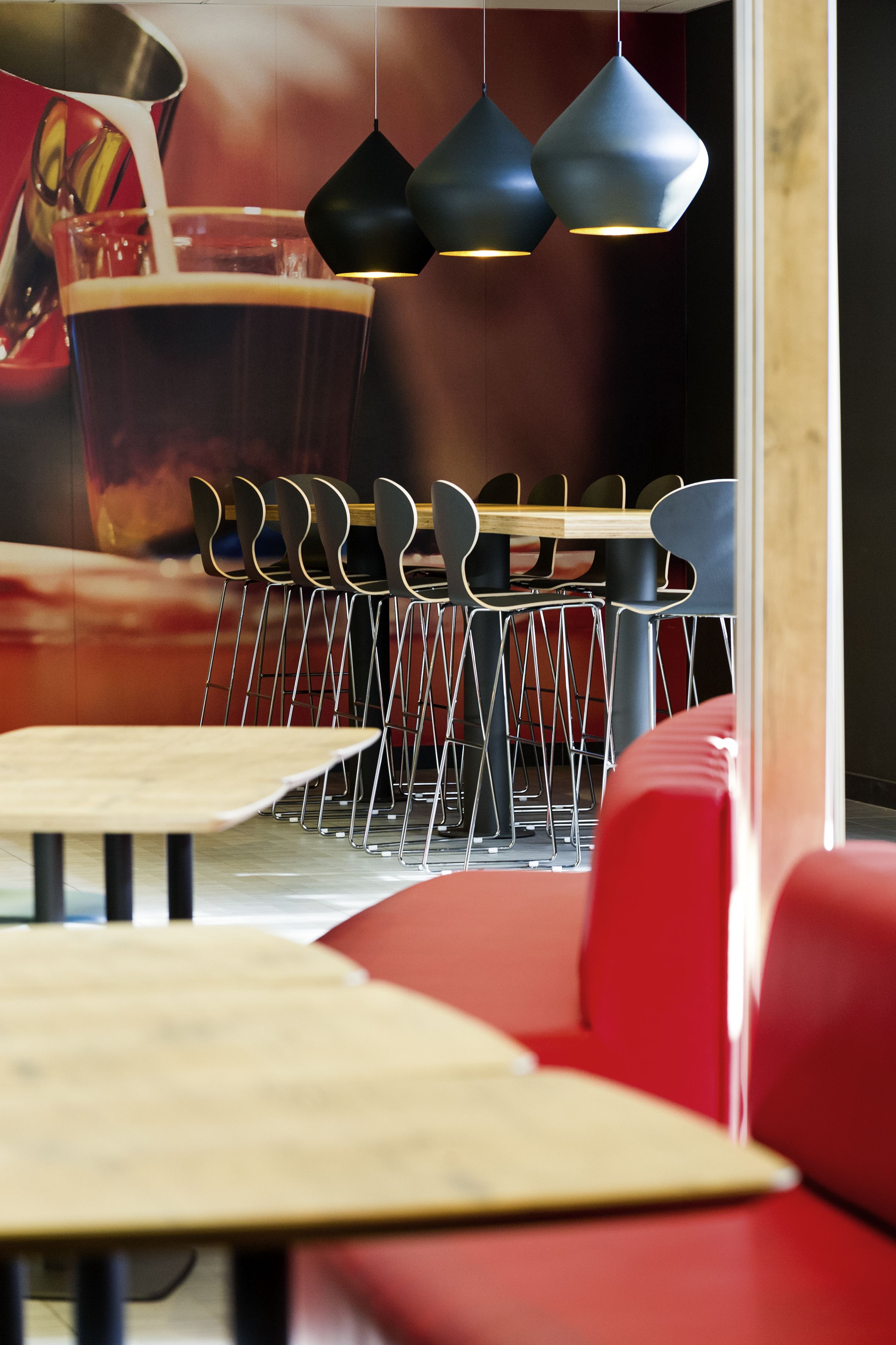 Een restaurantinterieur met een houten tafel, rode bekleding en hangende吊り灯.