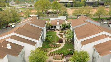 A courtyard with a central lawn, surrounded by buildings with brown roofs.