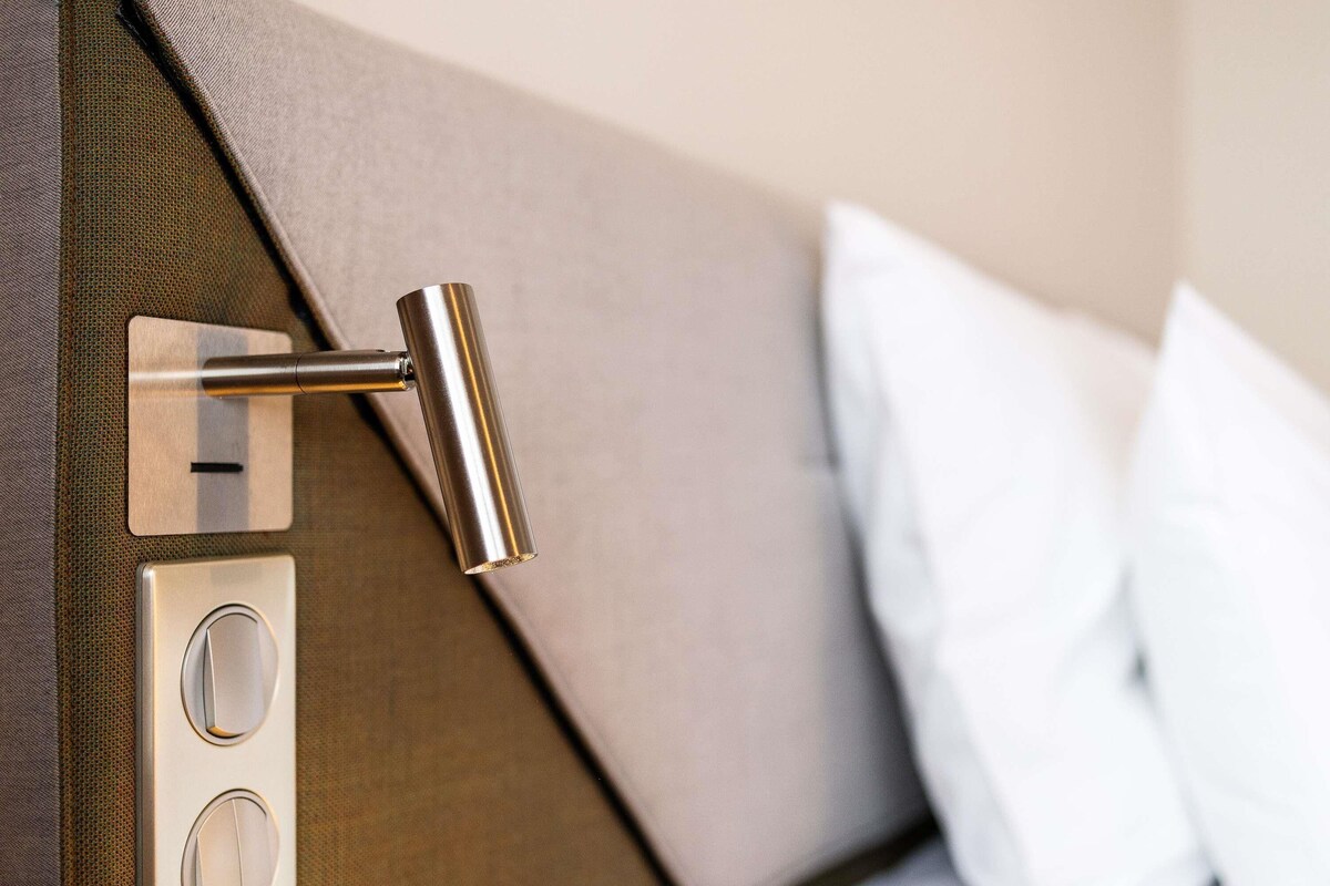 A modern bed with a metallic headboard, a control panel with buttons, and a white pillow.