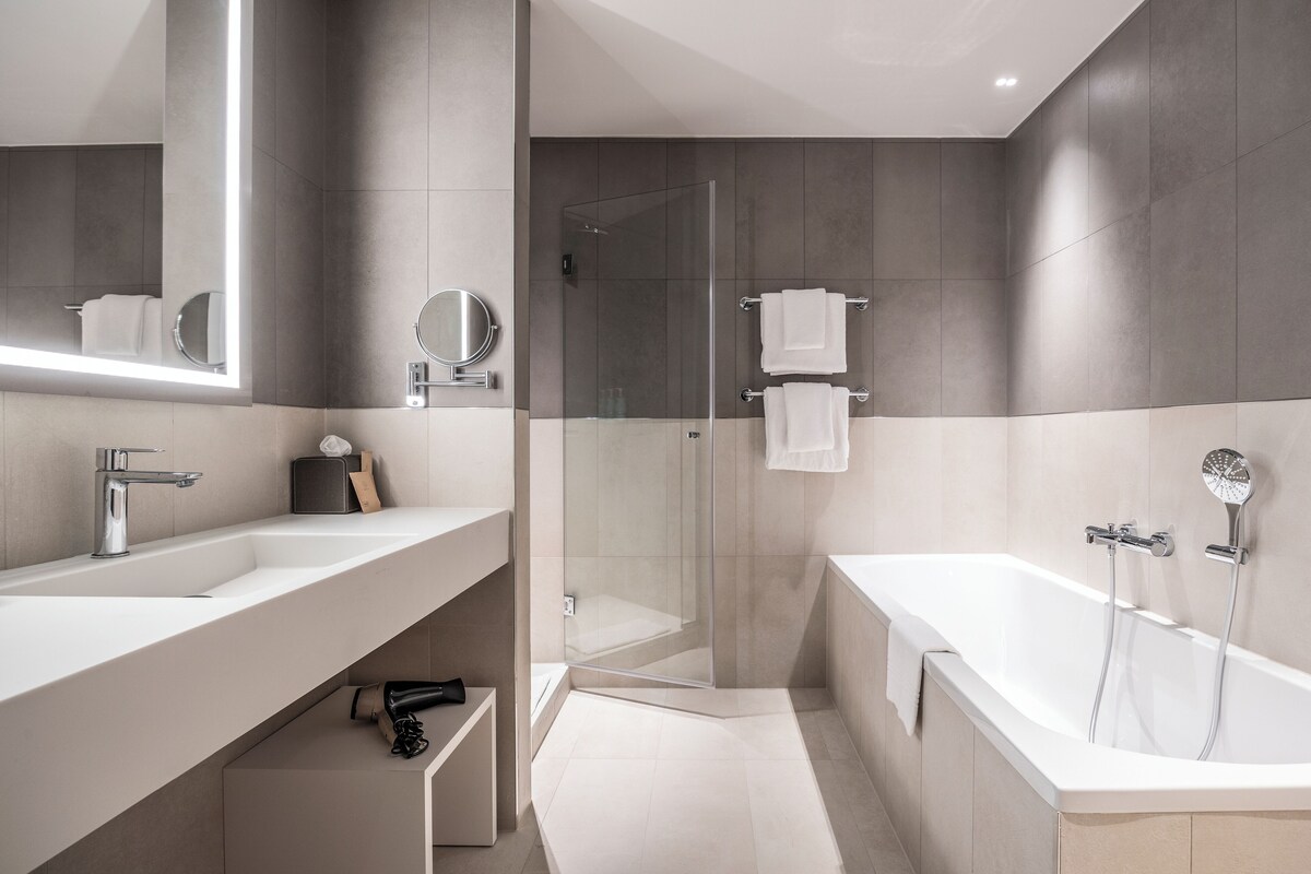 A modern bathroom with a large mirror, a shower, and a bathtub.