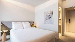 A modern hotel room with a large bed, a bedside table, a wall-mounted abstract art piece, and a door leading to another room. - Novotel Brugge Centrum (Bruges)