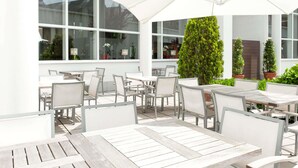 An outdoor patio with tables and chairs, large umbrellas, and potted plants. - Novotel Brugge Centrum (Bruges)