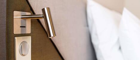 A modern bed with a metallic headboard, a control panel with buttons, and a white pillow.