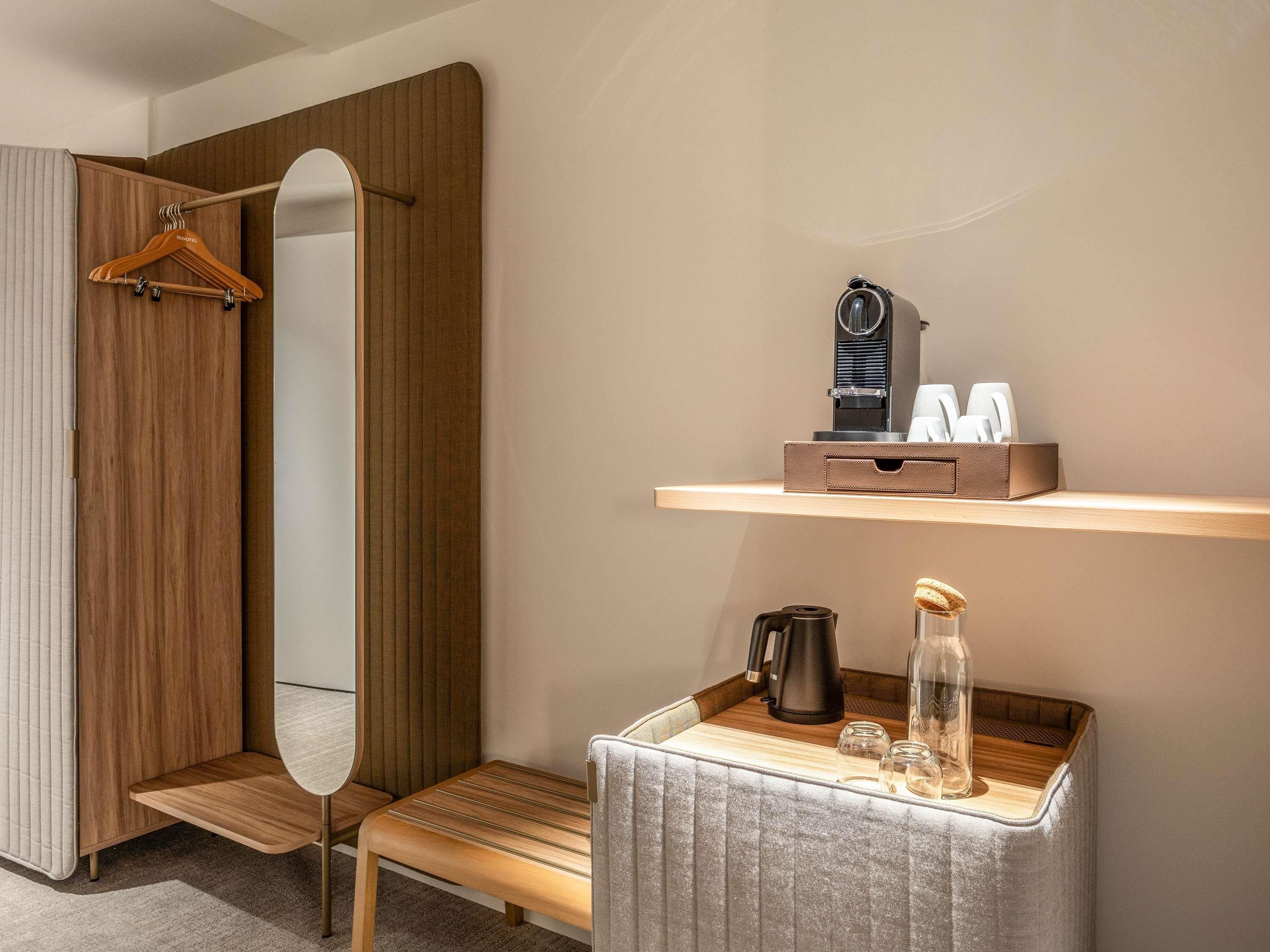 Une salle de bain moderne avec un meuble-lavabo en bois, un miroir, une étagère contenant des articles de toilette et un petit coin salon.