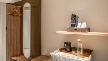 Une salle de bain moderne avec un meuble-lavabo en bois, un miroir, une étagère contenant des articles de toilette et un petit coin salon.