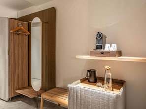 A modern bathroom with a wooden vanity, a mirror, a shelf with toiletries, and a small seating area. - Novotel Brugge Centrum (Bruges)