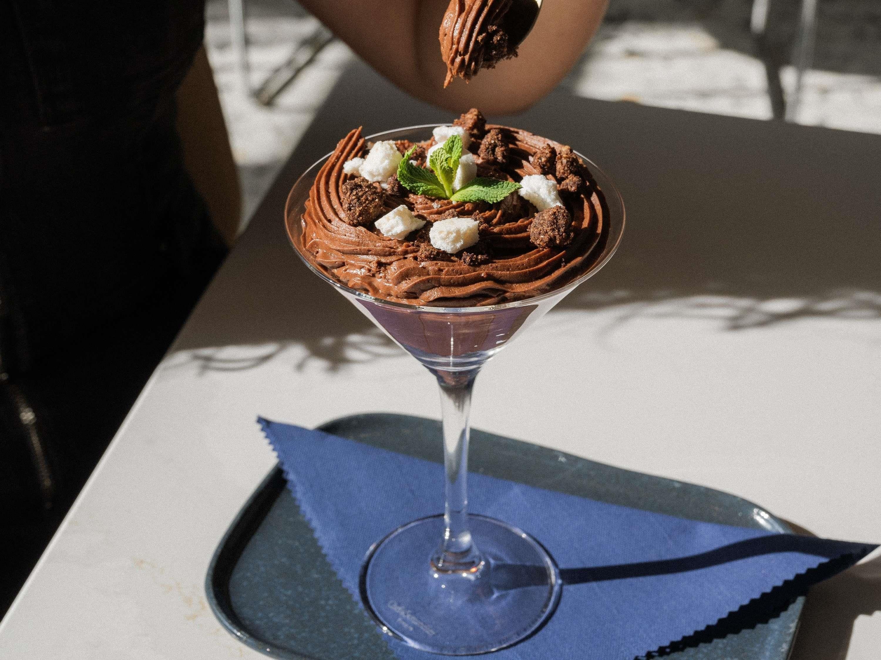 Un postre en una copa tipo martini sobre una mesa con servilleta azul.
