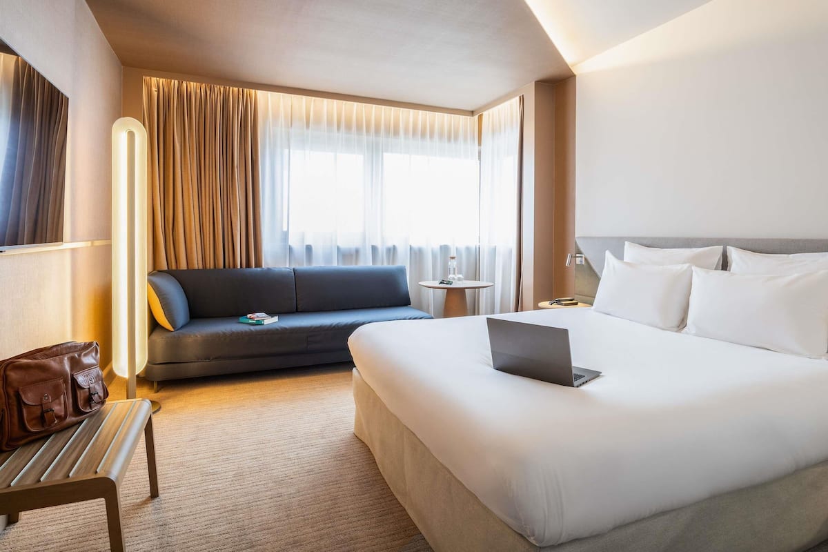 A hotel room with a bed, a sofa, a small table, and a chair.
