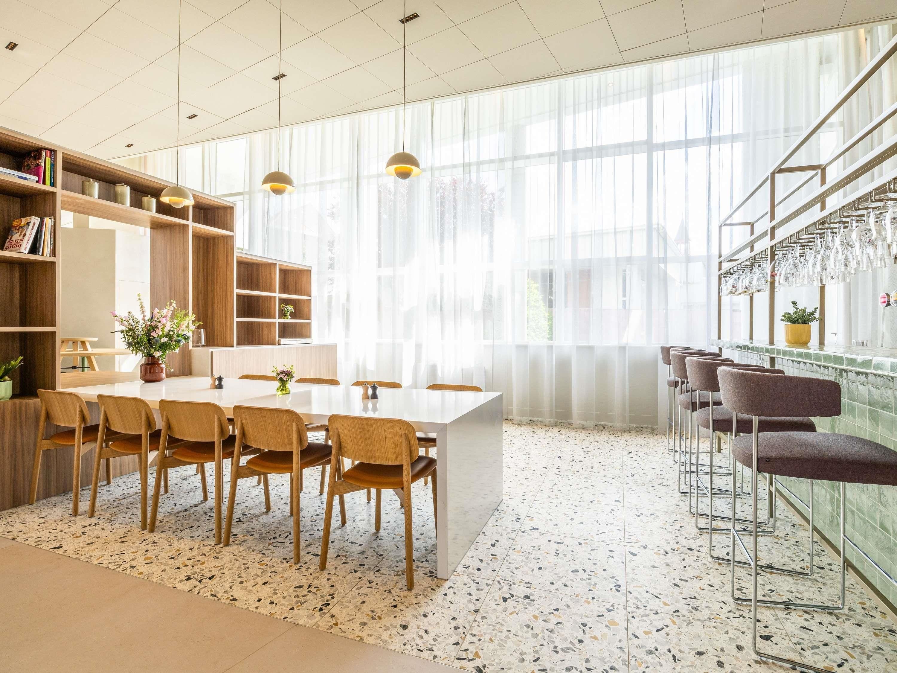 Een moderne keuken met een eethoek, grote ramen en een bar met krukken.