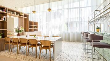 Een moderne keuken met een eethoek, grote ramen en een bar met krukken.