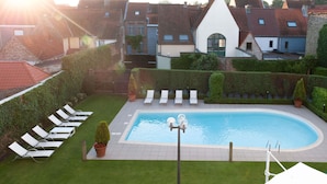 A swimming pool with lounge chairs, a small garden, and a view of residential buildings. - Novotel Brugge Centrum (Bruges)