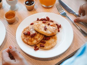 A plate of pancakes with syrup and dried berries. - Novotel Brugge Centrum (Bruges)