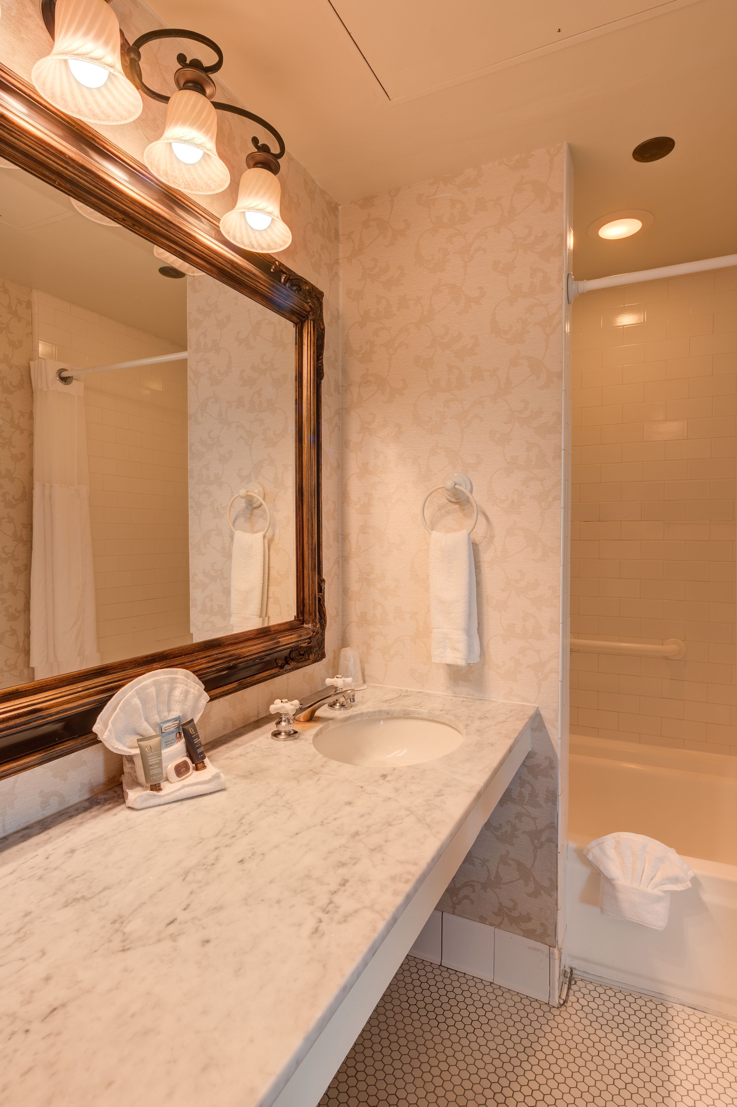 Une salle de bain avec un grand miroir, deux lavabos et une douche.