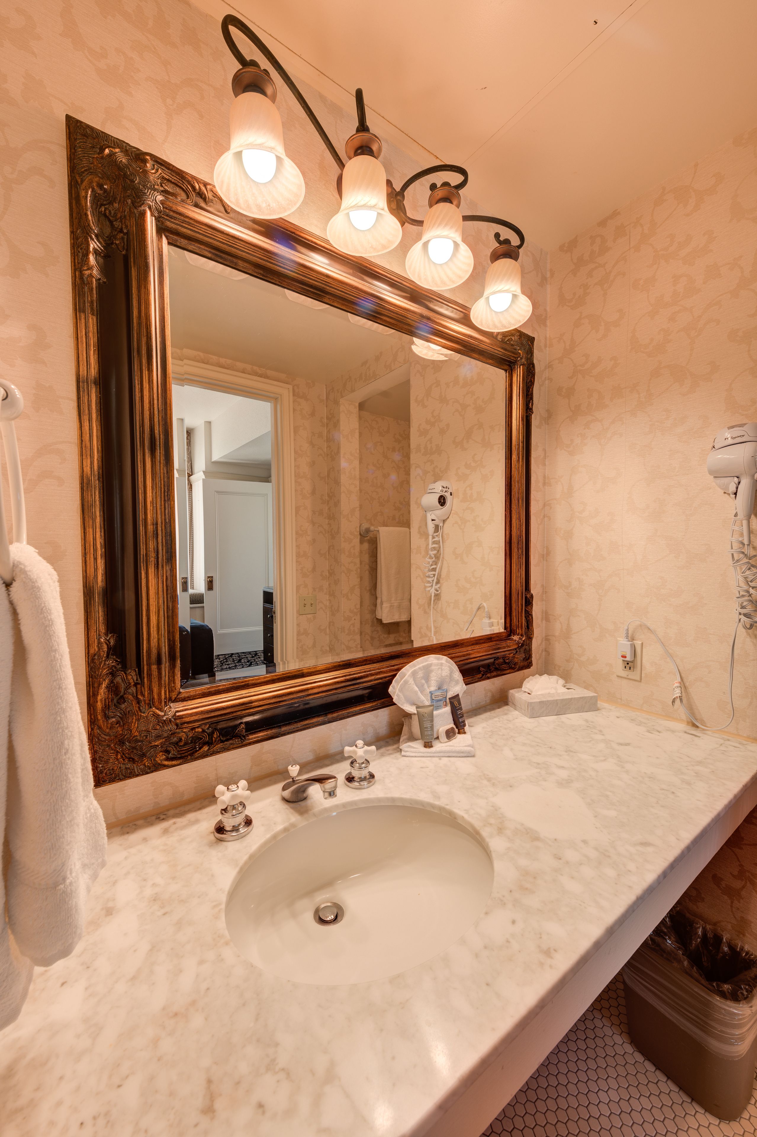 A bathroom with a large mirror, a sink, and a hairdryer.