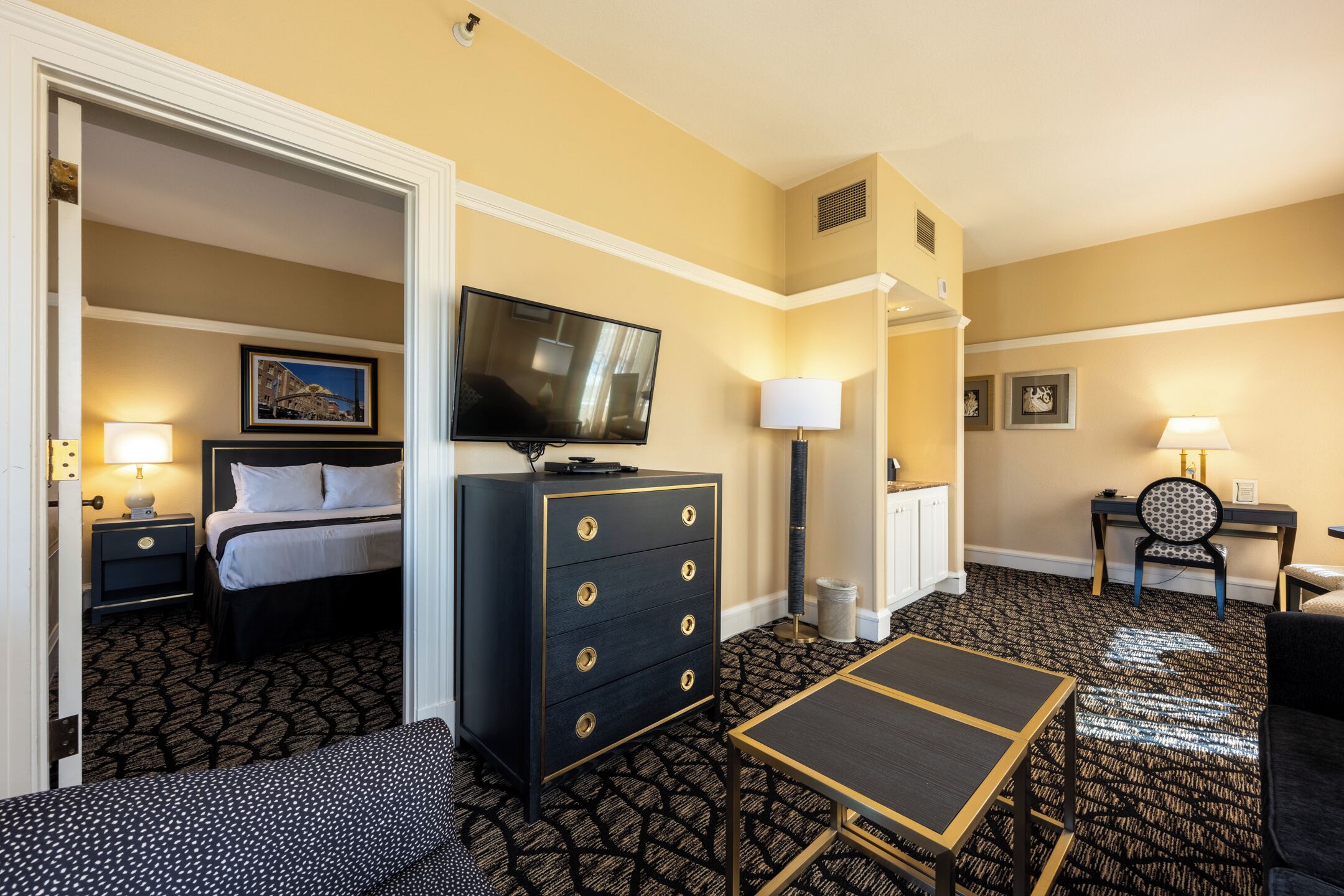Una habitación de hotel con cama, tocador, televisión, escritorio y una silla.