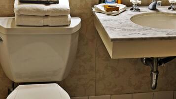 A bathroom with a toilet, sink, and mirror.