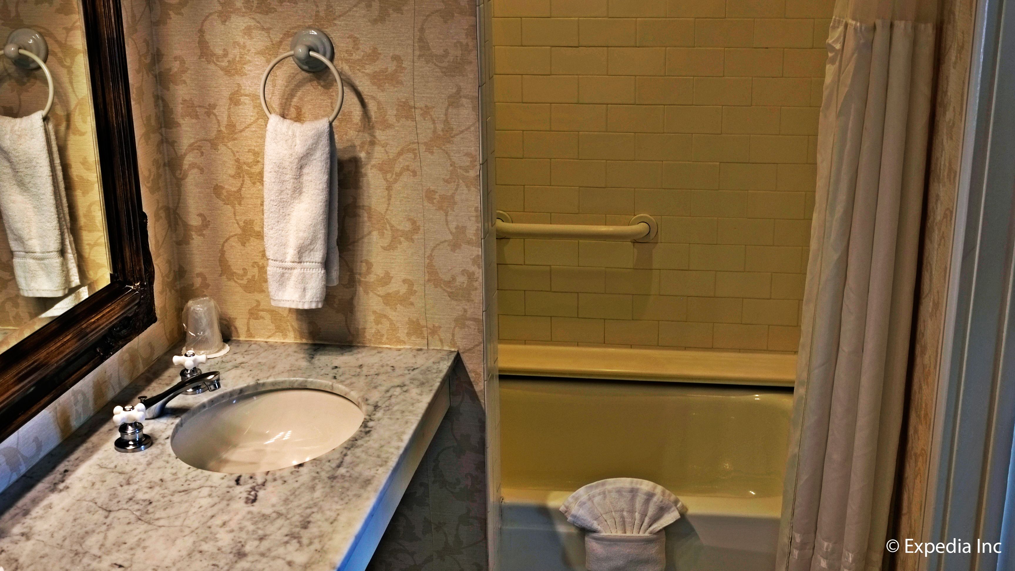 A bathroom with a marble sink, a towel ring, a glass, and a bathtub.