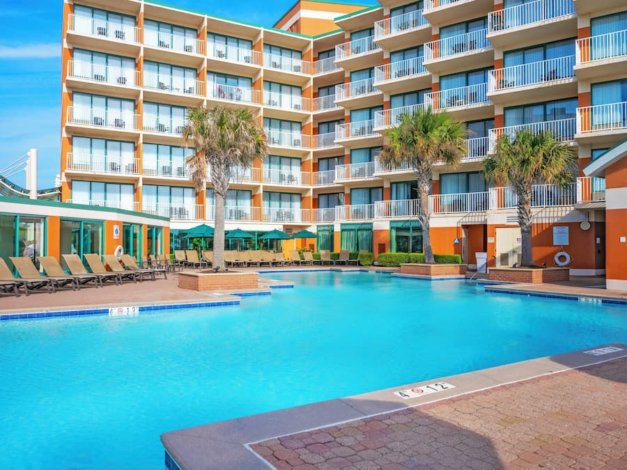 Un hôtel doté d’une grande piscine, de nombreux balcons et de chaises longues.