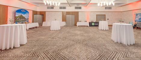 A spacious conference room with a high ceiling, multiple tables, and a patterned carpet.