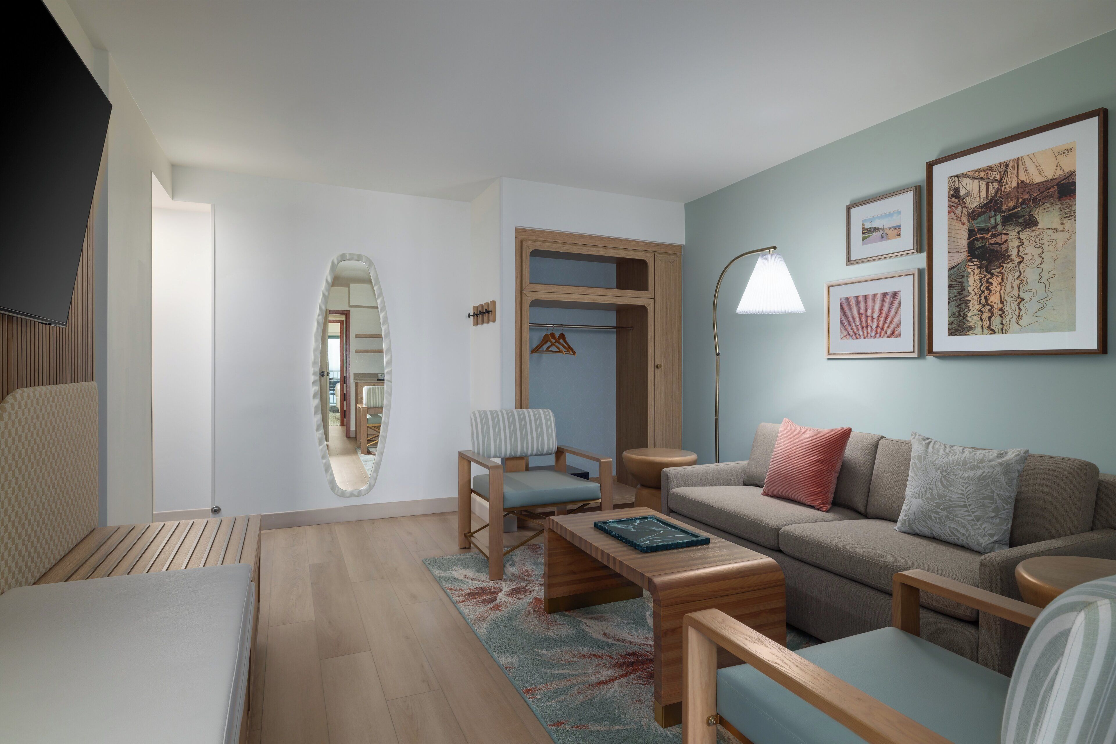 Ein modernes Wohnzimmer mit einer Couch, Sesseln, einem Couchtisch und einem Spiegel.