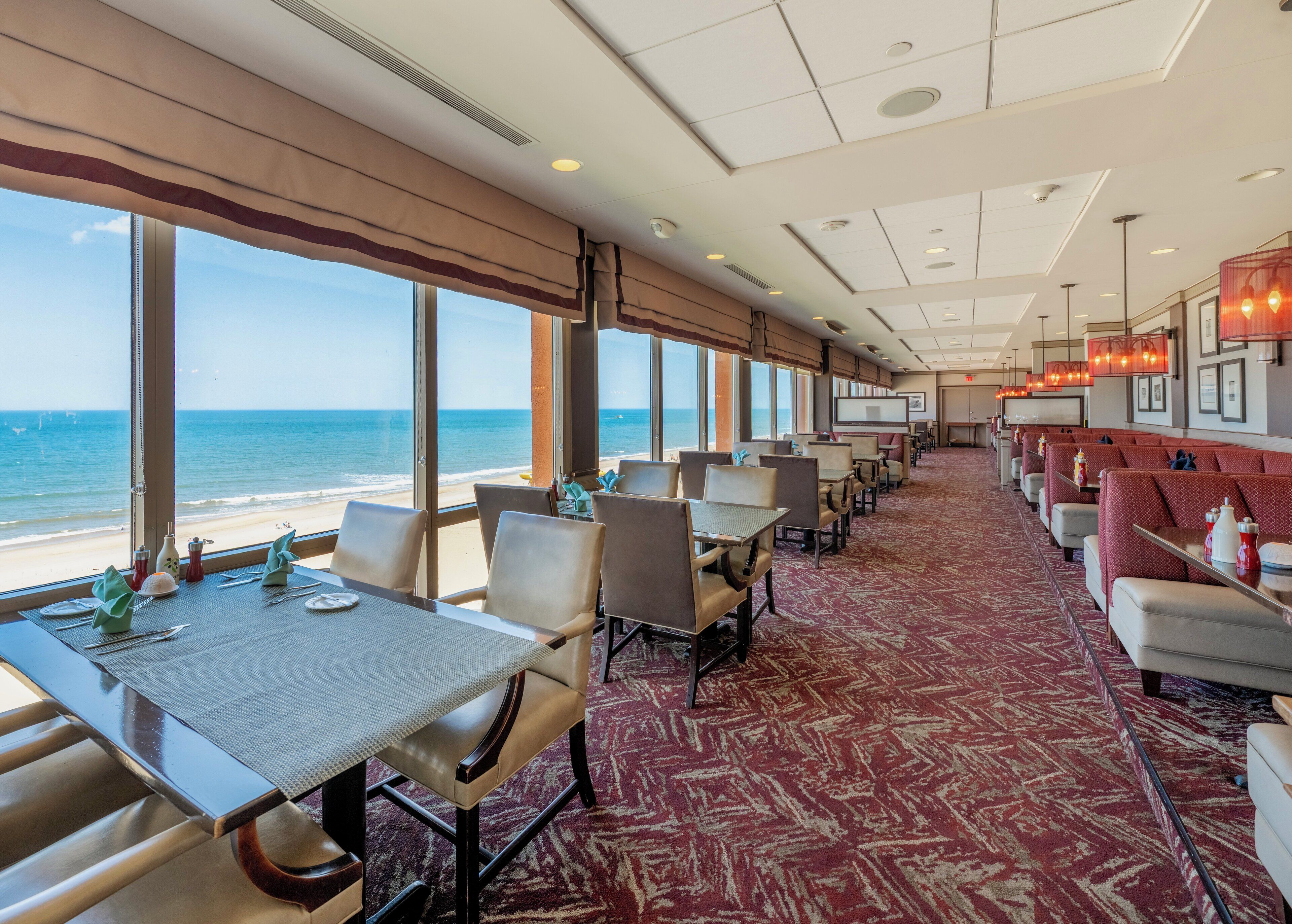 A restaurant with tables and chairs facing a beach view.