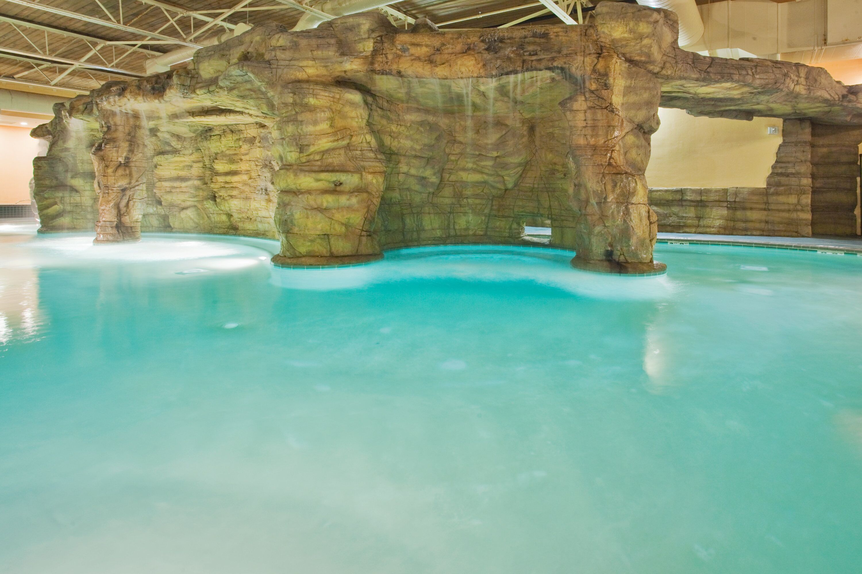 An indoor swimming pool with a rocky wall structure.