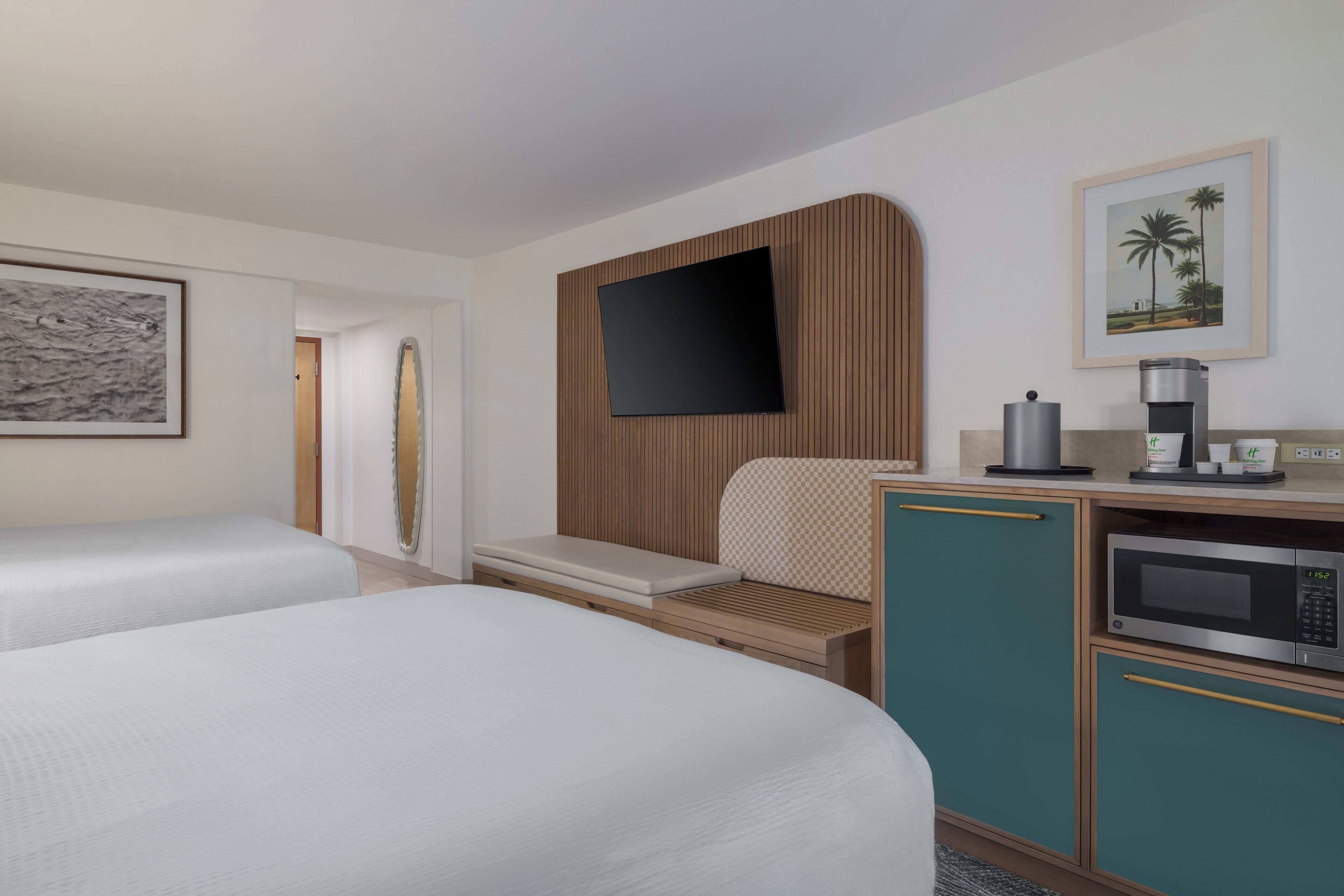 Een hotelkamer met twee bedden, een televisie, een koffiezetapparaat en een magnetron.