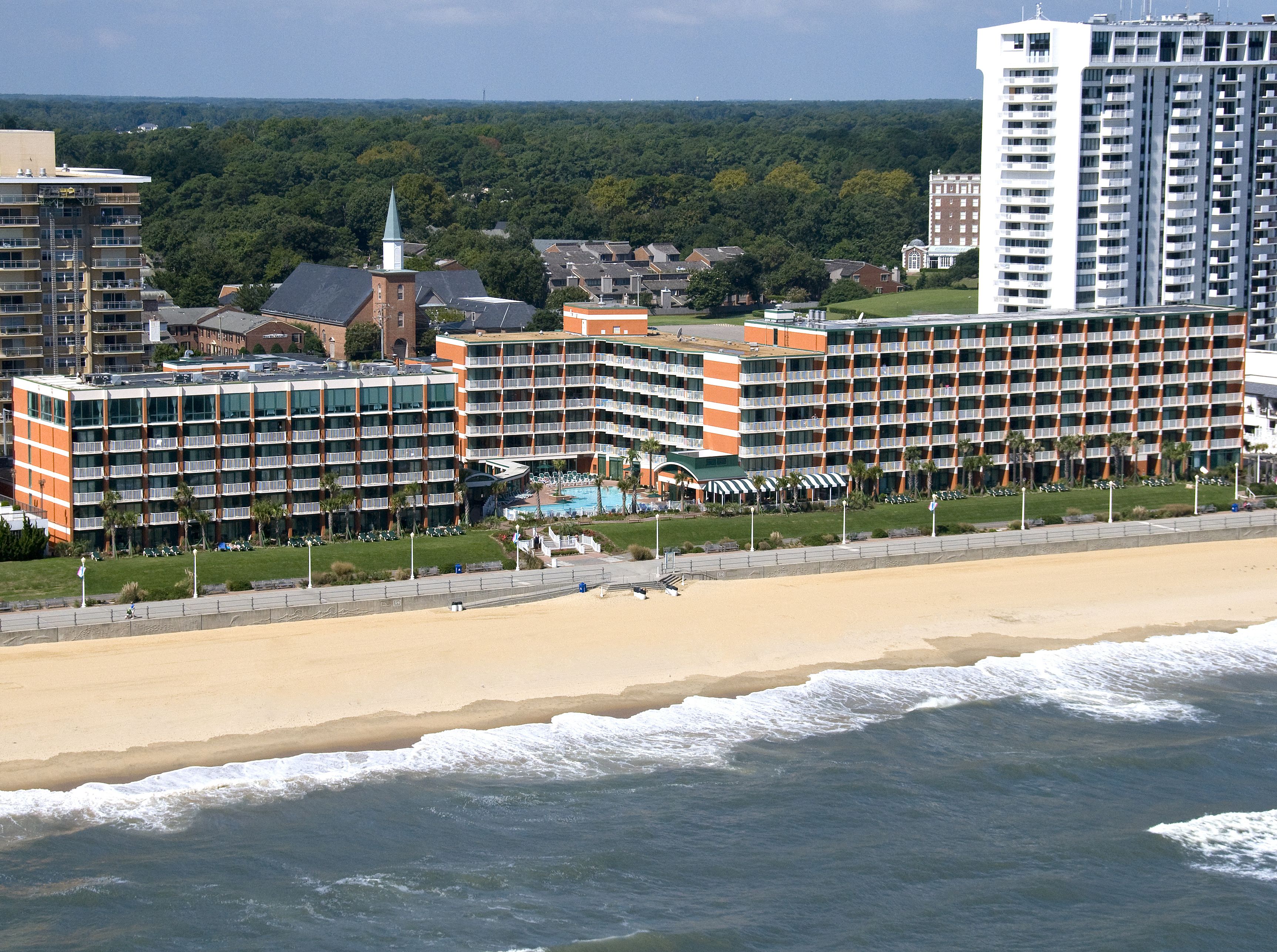 Ein Strandhotel mit mehreren Balkonen, einem Schwimmbad und Blick auf den Ozean.