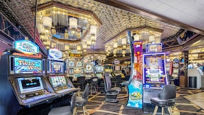 Un casino con múltiples máquinas tragamonedas, zonas de bar y una araña de cristal.