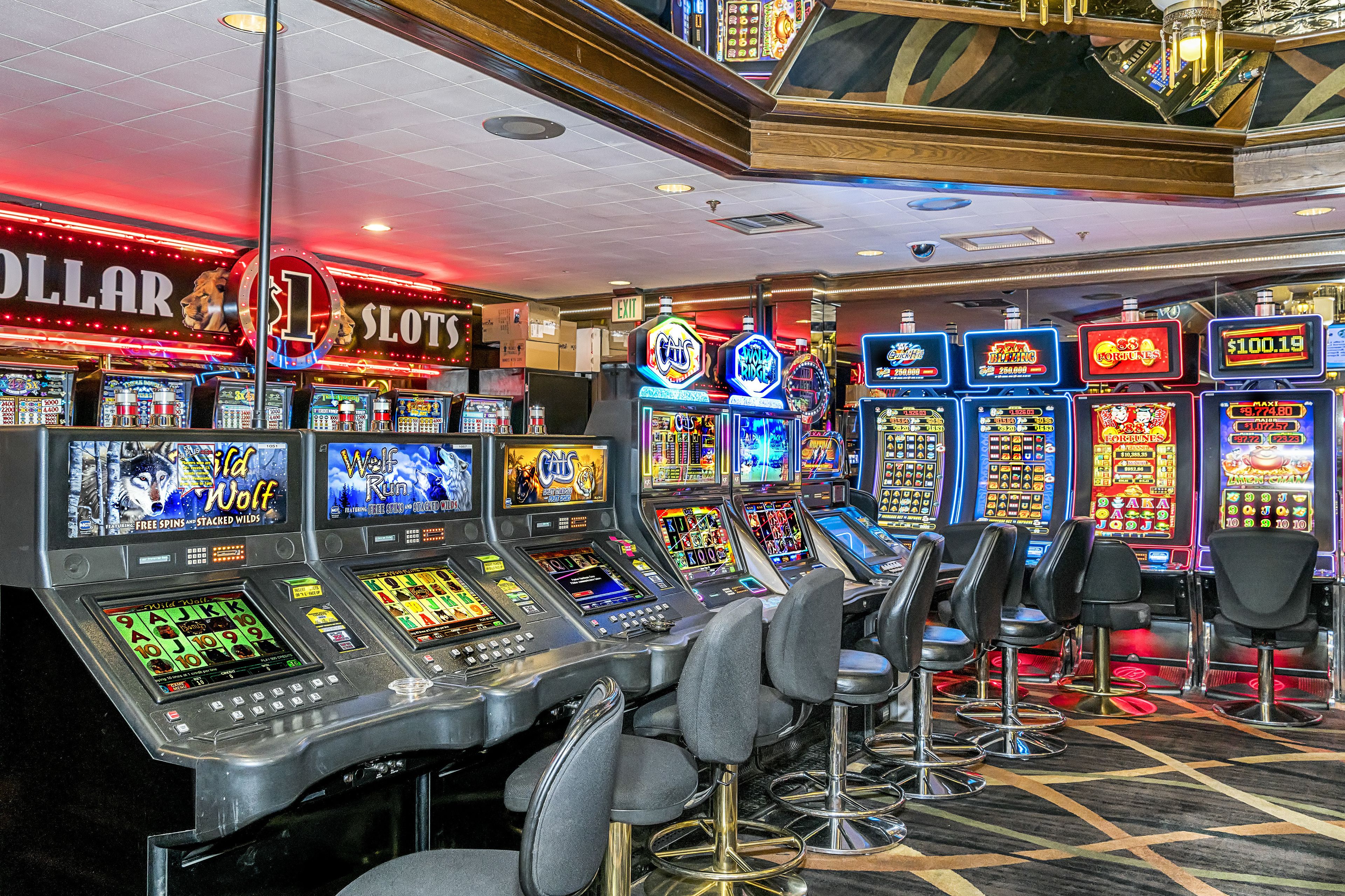 Een casino met meerdere gokkasten en barstoelen.