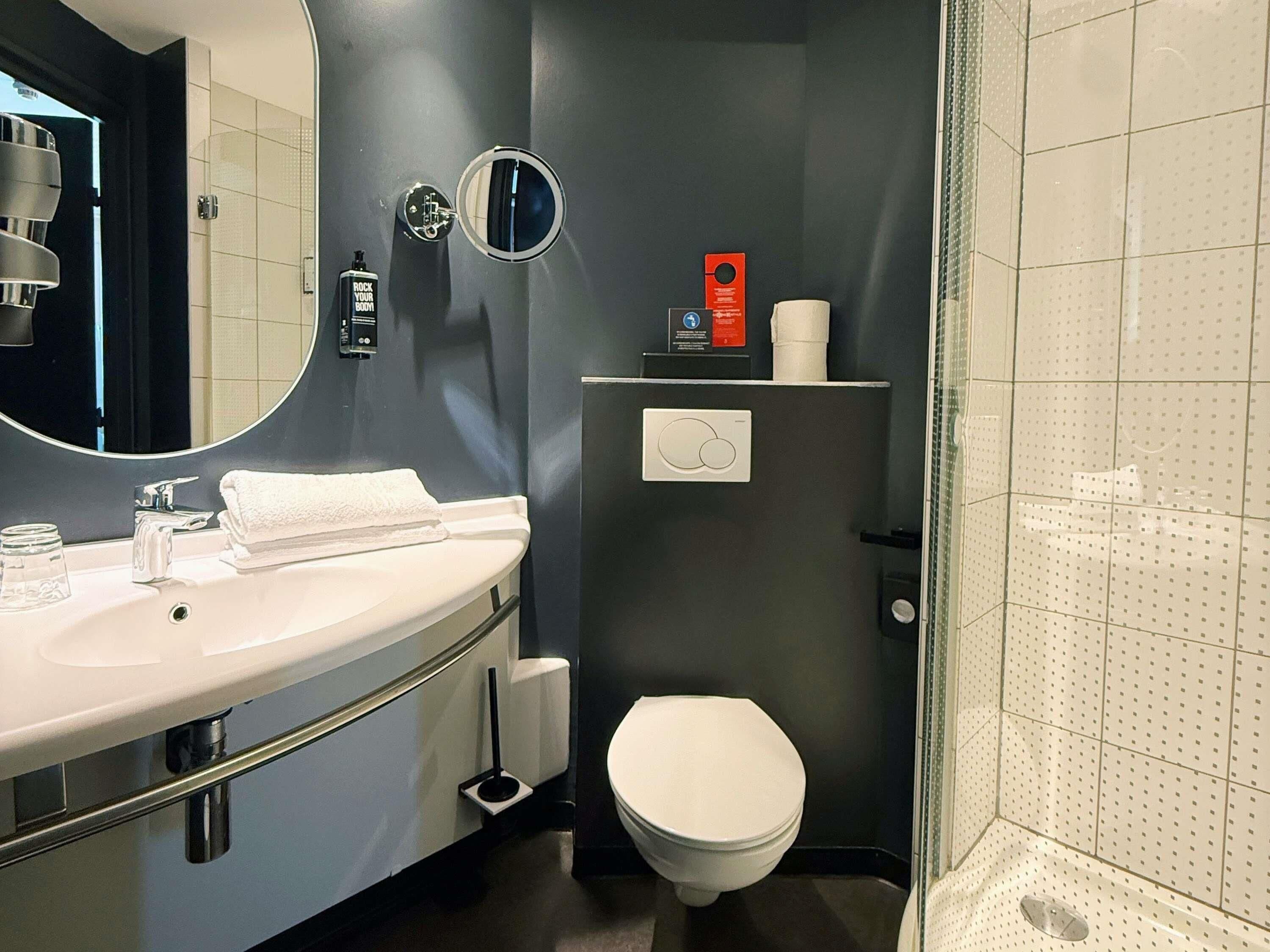 A modern bathroom with a white sink, mirror, and toilet.