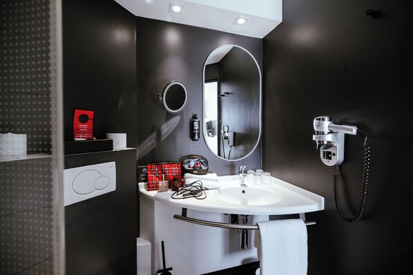 Un baño moderno con un lavabo blanco, dos espejos y un cabezal de ducha manual.