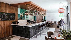 A modern bar area with a black marble counter, green cabinets, and a chalkboard menu.
