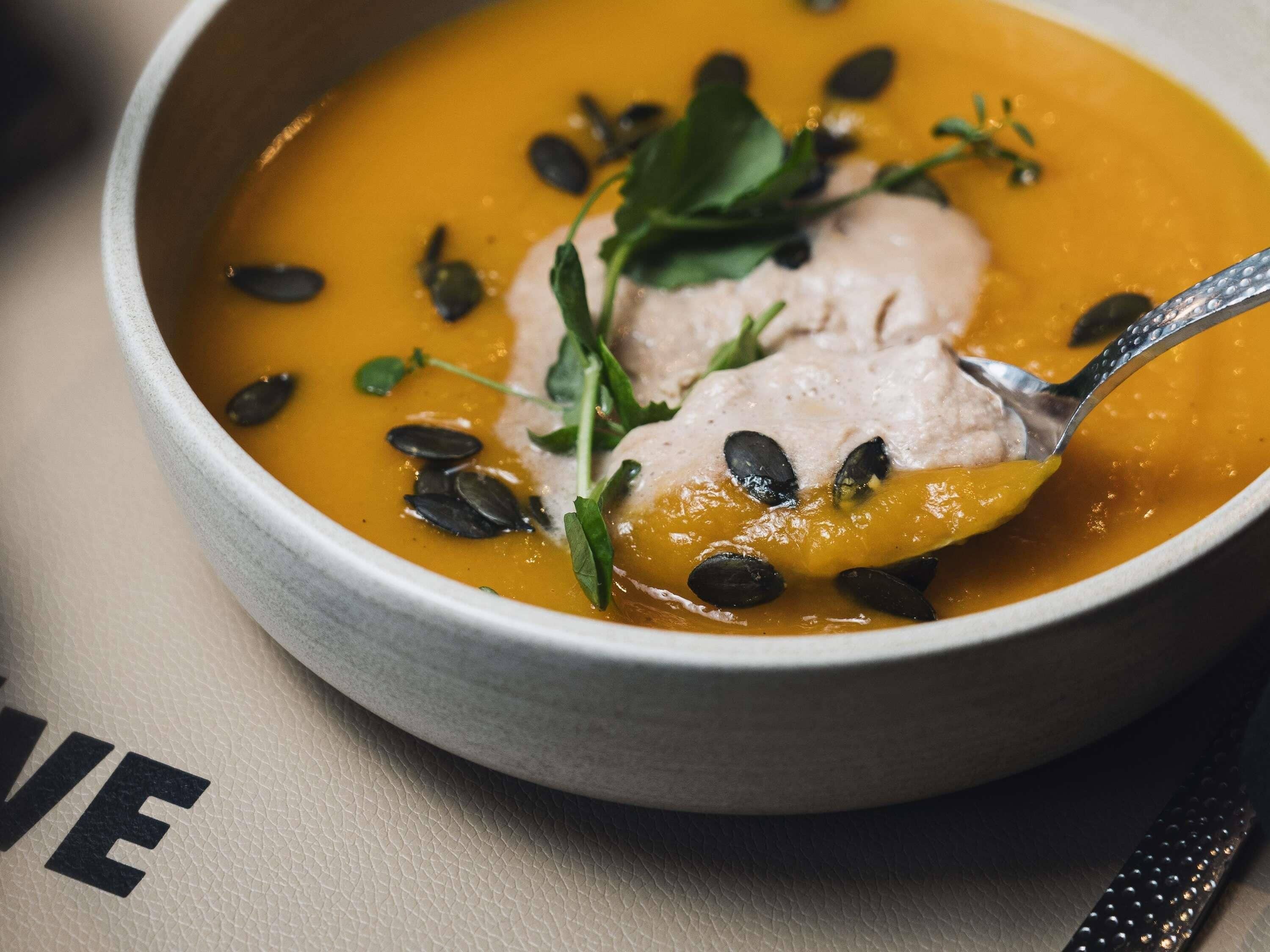 A bowl of soup with a garnish of seeds and greens.