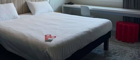 Habitación de hotel con una cama, un escritorio, una silla y una ventana con vistas al exterior.