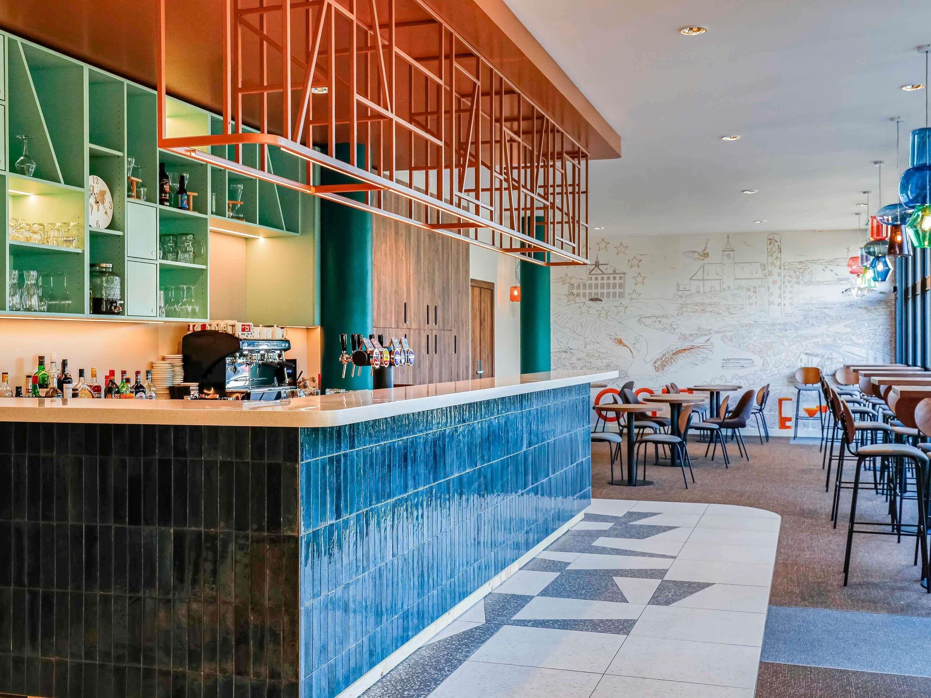 A modern bar area with a counter, seating, and a mural on the wall.