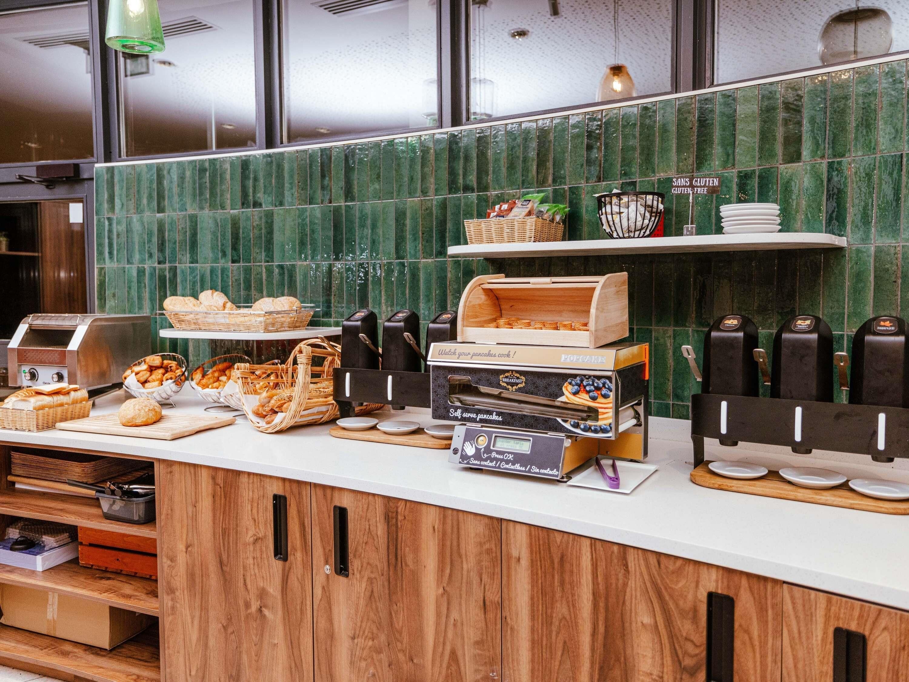Una barra de desayuno con varios pasteles, un tostador y una cafetera.