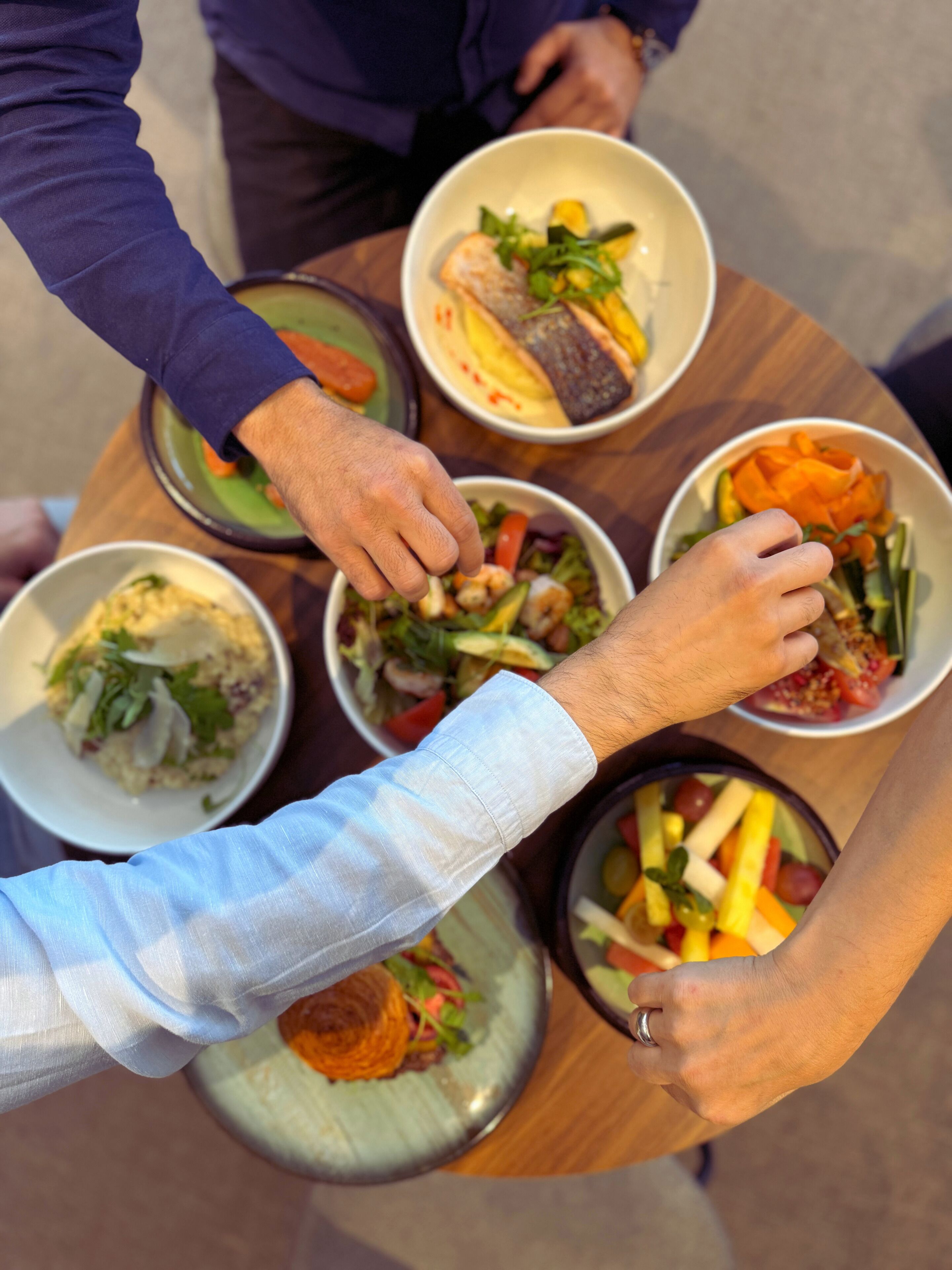 A round table with multiple dishes, including salads and a fish dish.