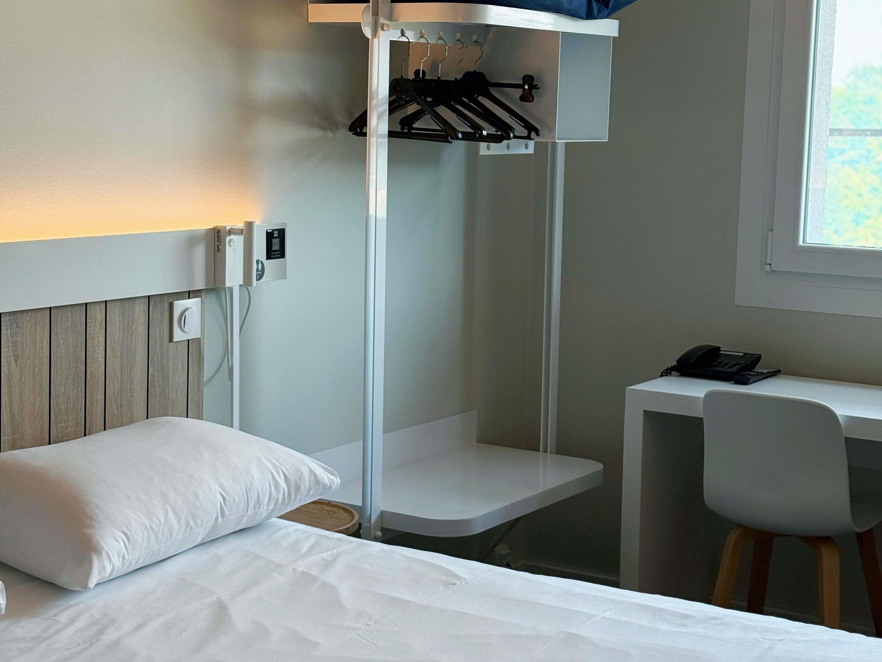 A hotel room with a bed, a desk, and a chair.