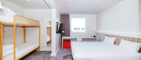 A hotel room with a bunk bed, a single bed, a desk with a chair, a TV, and a window with curtains.