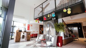 A modern lobby with a reception desk, seating area, and a staircase.