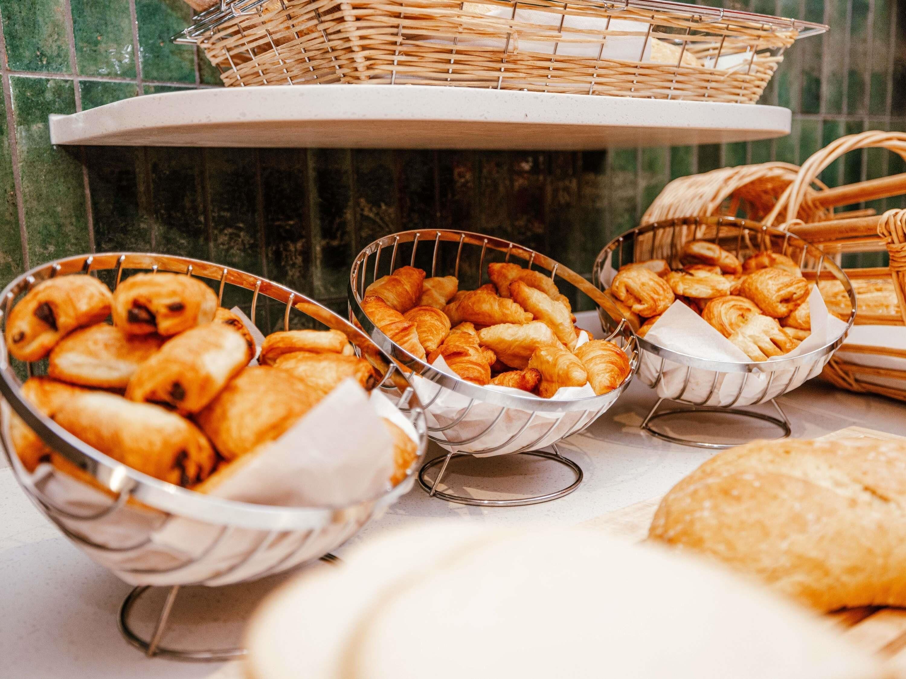 Un buffet proposant une variété de produits de boulangerie présentés dans des paniers en métal.
