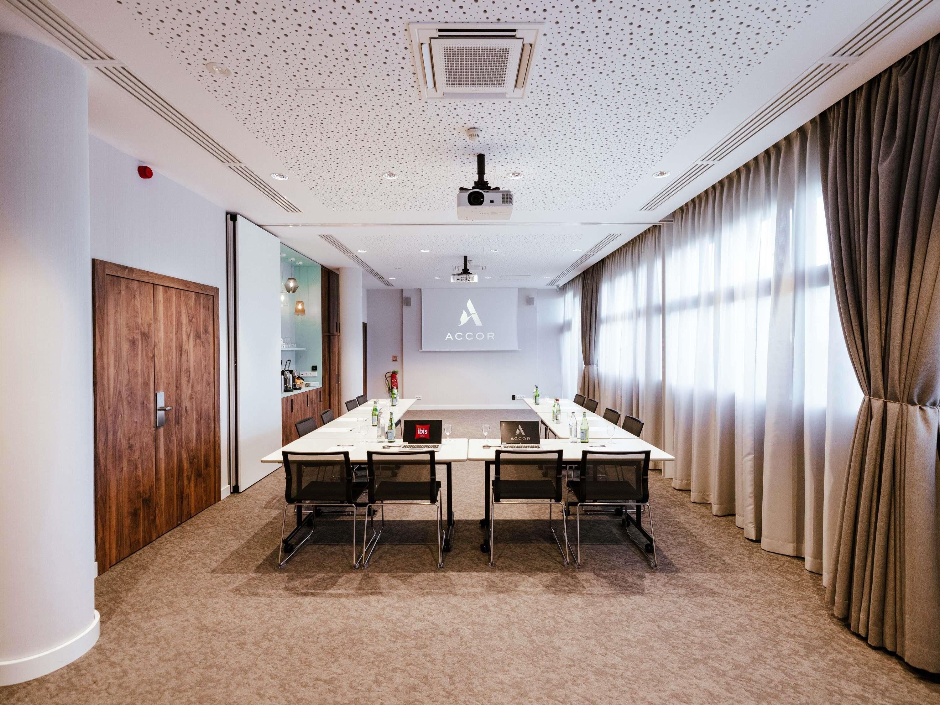A conference room with a long table, chairs, a projector, and a screen displaying the ACCOR logo.