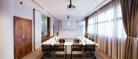 A conference room with a long table, chairs, a projector, and a screen displaying the ACCOR logo.