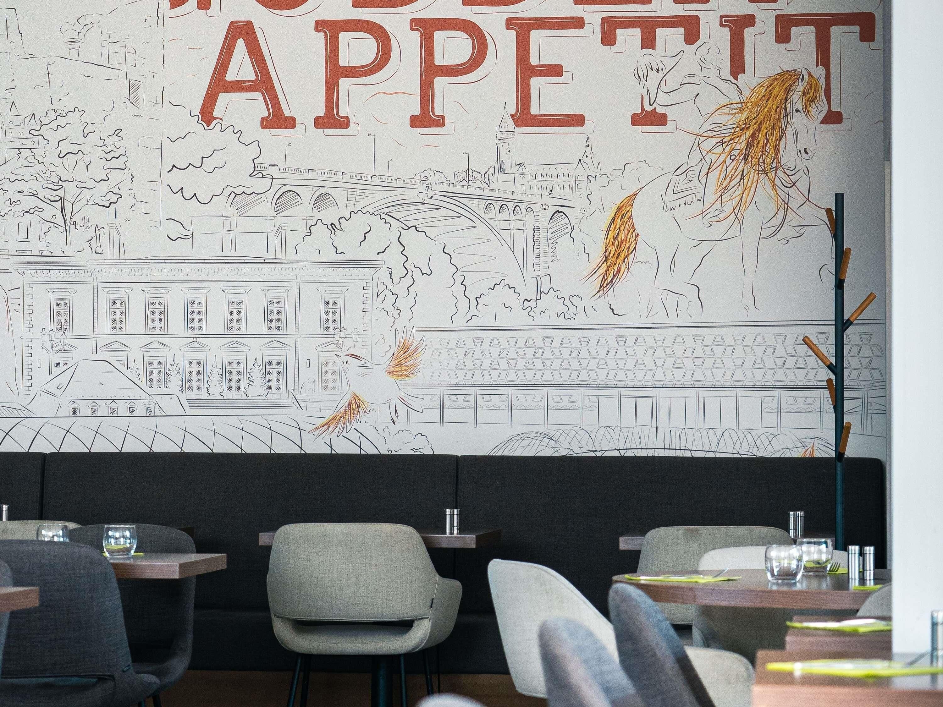 Een restaurantinterieur met een muurschildering, tafels, stoelen en een bar.