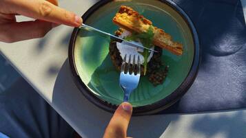 A person dining at a table with a plate of food, a fork, and a glass of water.