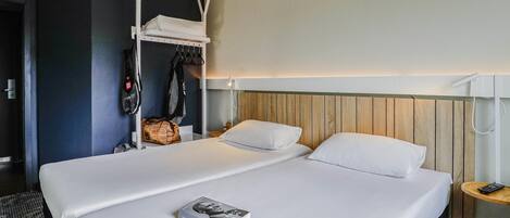 A hotel room with a large bed, a wooden headboard, a small bedside table, and a hanging chair.